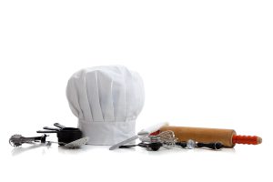 several baking utensils with a chef's hat on white background